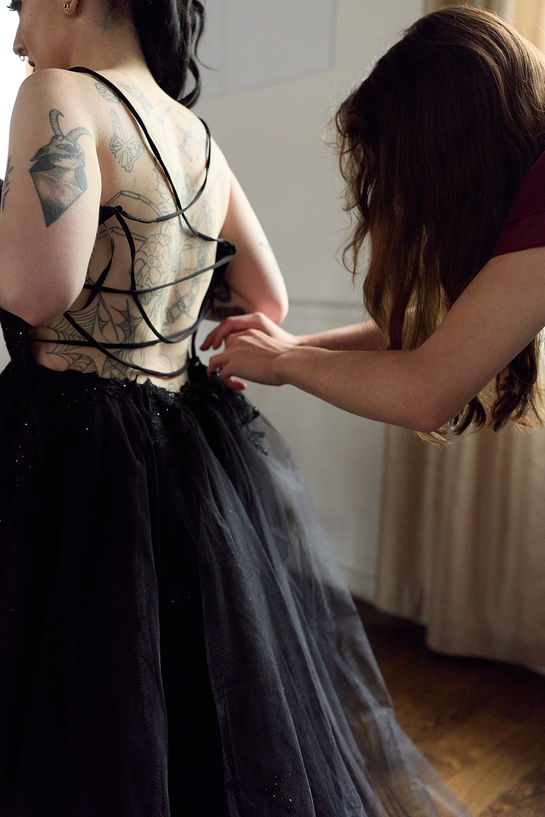 Maid of honor lacing up the corset back of the bride's black wedding gown