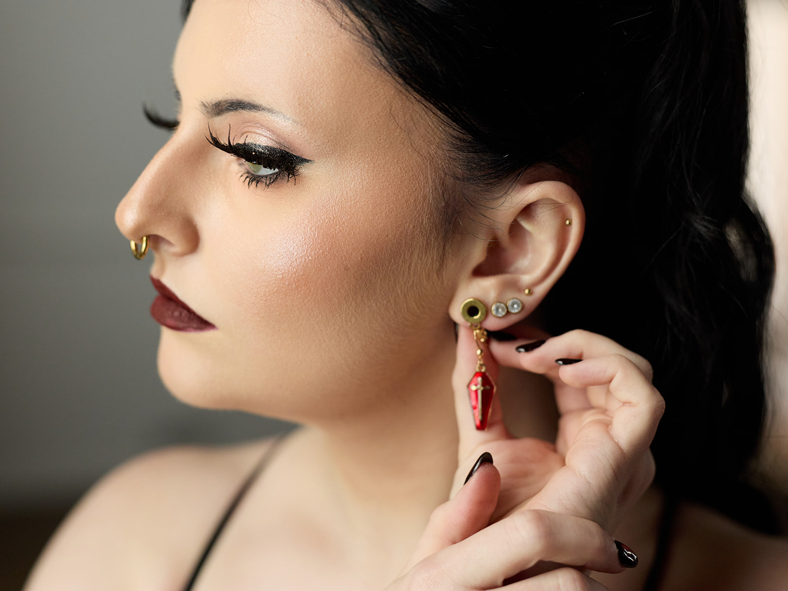 Profile portrait of the bride putting on red earrings