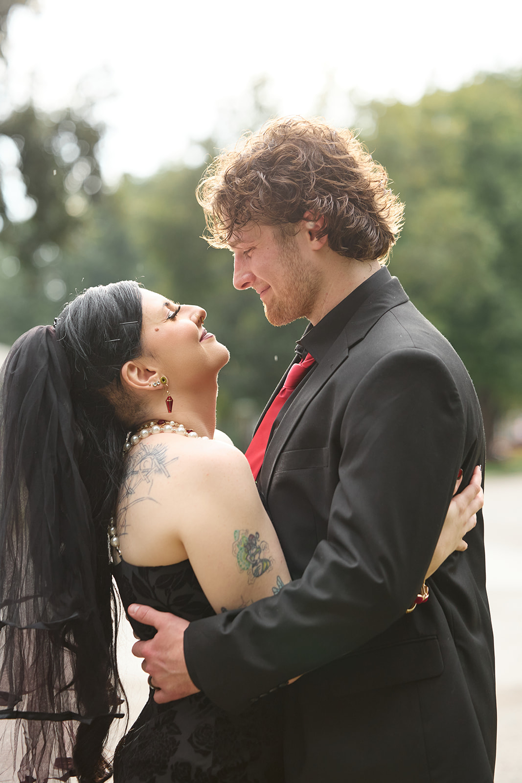 Bride laughing with her head thrown back in the groom's arms outdoors after the rain