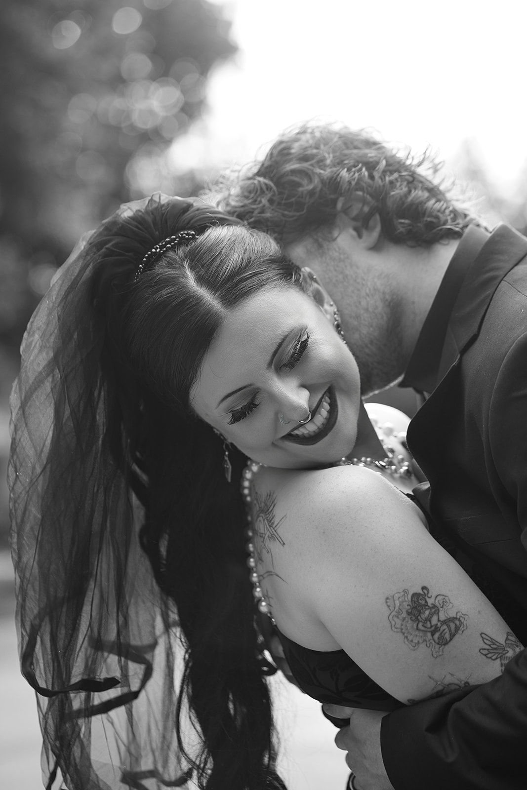 Black and white portrait of the bride laughing as the groom holds her close